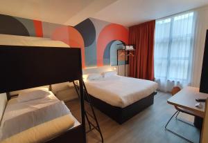a hotel room with two beds and a desk at B&B HOTEL Hasselt in Hasselt