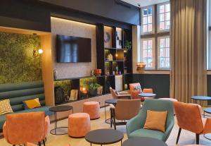 a waiting room with chairs and tables and a tv at B&B HOTEL Hasselt in Hasselt