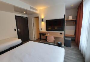 a hotel room with a bed and a flat screen tv at B&B HOTEL Hasselt in Hasselt