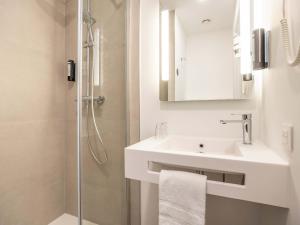 a white bathroom with a sink and a shower at B&B HOTEL Namur in Namur