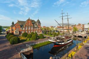 un barco en el agua frente a un edificio en Kedi Hotel Papenburg en Papenburg