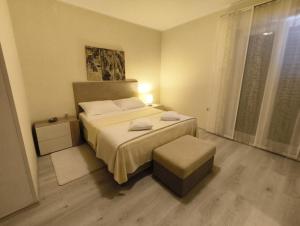 a bedroom with a bed and a ottoman in it at Apartman Maledi in Baška