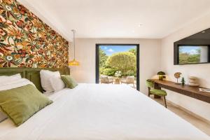 a bedroom with a large white bed and a desk at Capucines Hotel Saint Tropez in Saint-Tropez