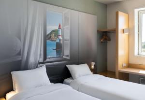 a room with two beds and a window with a lighthouse at B&B HOTEL Lorient Caudan in Caudan