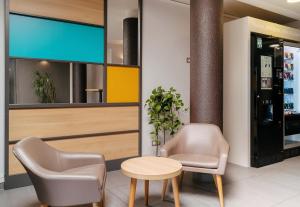 a lobby with two chairs and a table and a tv at B&B HOTEL Lorient Caudan in Caudan +17 photos