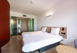 a bedroom with a large white bed and a table at B&B HOTEL Lully 3 Lakes in Estavayer-le-Lac