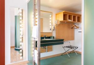 a small kitchen with a sink and a mirror at B&B HOTEL Lully 3 Lakes in Estavayer-le-Lac