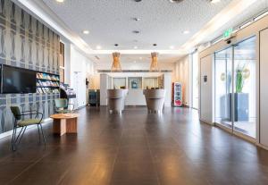 a lobby with chairs and a television in a building at B&B HOTEL Lully 3 Lakes in Estavayer-le-Lac +23 photos