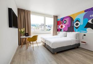 a hotel room with a bed and a large window at B&B HOTEL St Gallen in St. Gallen