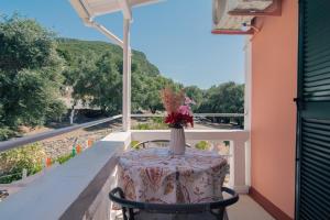 a table with a vase of flowers on a balcony at Lisipio Studios by Eleni in Paleokastritsa