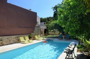 a swimming pool with chairs and a house at Villa Verde Petra in Arménoi