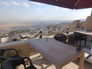 a table and chairs on a balcony with a view at Gılgamesh Maria butik otel in Mardin