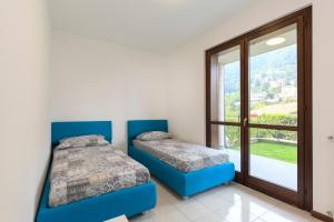two beds in a room with a window at Residence Borgo Castello B1 Apartment in Argegno