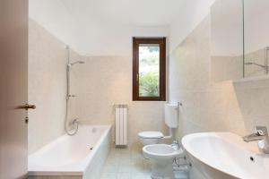 a bathroom with a tub and a toilet and a sink at Residence Borgo Castello B1 Apartment in Argegno