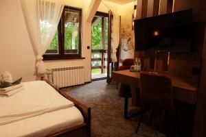 a bedroom with a bed and a desk and a television at Zajazd U Dudziarza in Kościan