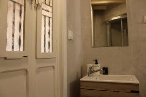 a bathroom with a sink and a mirror and a door at Litharaki Guest House in Ano Syros