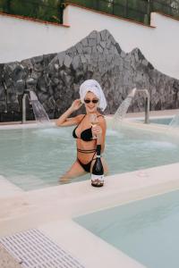 a woman in a bikini sitting in a swimming pool at Vesuvio Inn Bed & Wine Experience in Boscotrecase