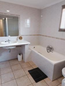 a white bathroom with a tub and a sink at Pecan Farm Guesthouse in Louis Trichardt +53 photos