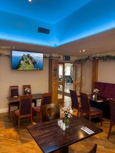 Ein Zimmer mit Tischen und Stühlen und einem Fernseher an der Wand. in der Unterkunft Ring of Kerry Hotel in Cahersiveen