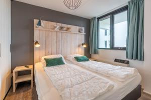 a bedroom with a large bed with two green pillows at Appartementencomplex Juliana 94 in De Koog