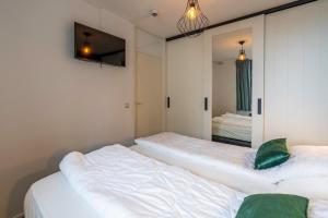 two beds in a room with a mirror at Appartementencomplex Juliana 94 in De Koog +4 photos