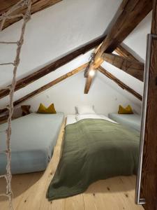 two beds in a attic room with wooden beams at Dachboden Loft in Laax