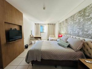 a bedroom with a bed and a flat screen tv at Betel Flat Executive Praia Boa Viagem in Recife