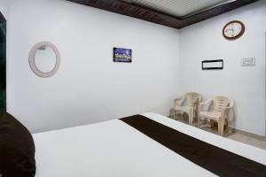 a bedroom with a bed and two chairs and a clock at Hotel O Raj Resort in Sopāra +22 photos