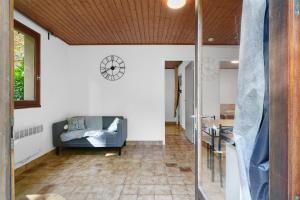 a living room with a couch and a clock on the wall at 8.Les papillons option clim-4 pers in Calviac