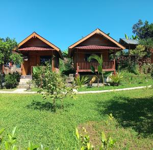 a house with a green yard with two buildings at Tetebatu Sunrise Homestay in Tetebatu