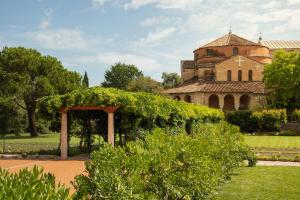 an old building with a ivy hedge in front of a garden at Locanda Cipriani in Torcello