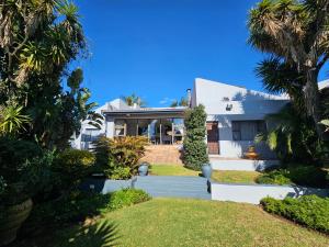 a white house with palm trees in front of it at PhysEQFiT Guesthouse in Centurion
