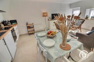 a kitchen with a table with plates and a vase of fruit at Les pierres d'armor in Vildé-Guingalan +17 photos