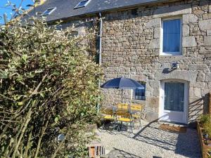 a stone house with a table and an umbrella at Les pierres d'armor in Vildé-Guingalan