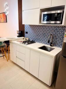 a white kitchen with a sink and a microwave at Bello apartamento con piscina cerca del mar in San Juan del Sur