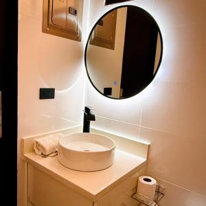 a bathroom with a sink with a round mirror at Bello apartamento con piscina cerca del mar in San Juan del Sur +3 photos