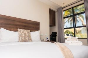 a bedroom with a large bed with a large window at Purpose International Hotel Eastlea in Harare