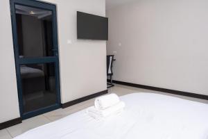 a room with a bed with a mirror and a tv at Purpose International Hotel Eastlea in Harare