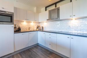 a white kitchen with white cabinets and appliances at Appartementencomplex Juliana 94 in De Koog