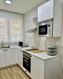 a kitchen with white cabinets and a stove top oven at URDAIHOME SUITES & BIKEs in Guernica y Luno +62 photos