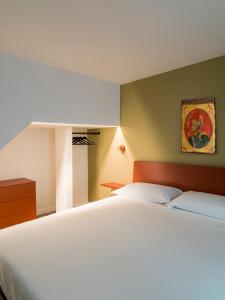 a bedroom with a large white bed and a painting at Palazzo Settanta in Catania
