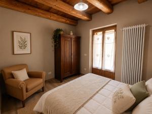a bedroom with a bed and a chair and a window at Appartamento Alta Valle Maira - Tibert in Ponte Maira