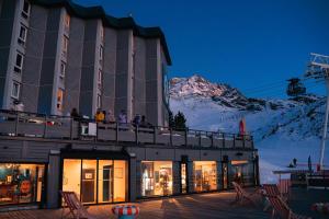 people on a balcony of a building with a mountain at Fahrenheit Seven Val Thorens in Val Thorens