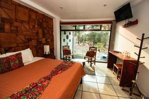a bedroom with a bed and a television and a window at Hotel Boutique Acocalli in San Juan Teotihuacán