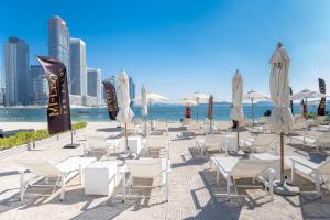a group of chairs and umbrellas on a beach at Mileo Hotel The Palm in Dubai