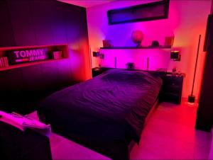 a bedroom with a bed with pink lights on it at jolie appartement in Seraing