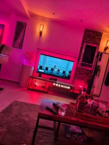 a living room with pink lighting and a tv at jolie appartement in Seraing +5 photos