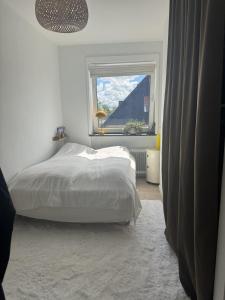 a white bedroom with a bed and a window at Hygge Home Aalborg, Free Parking & 15 Min to City Centre in Nørresundby