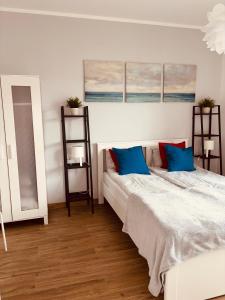 a bedroom with a bed with blue pillows at Apartamenty Nadmorska in Rowy
