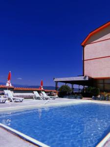 a swimming pool with chairs and a building and the ocean at Villa Marija - Izgrev in Star Dojran
